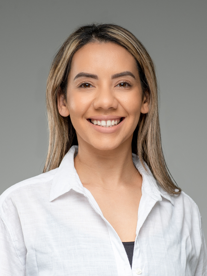 A successful female entrepreneur poses in front of a grey background during a headshot session